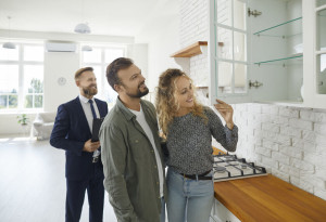 Couple buying house, meeting with real estate agent and looking around rooms in new home